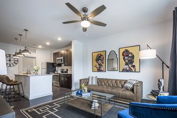 A living room with a brown couch and a ceiling fan.